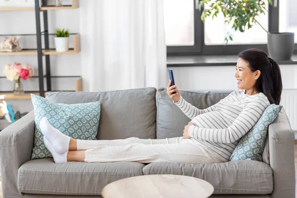 Mujer embarazada feliz con teléfono inteligente en casa — Foto de Stock