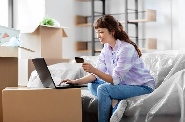 Mulher com laptop e cartão de crédito na nova casa — Fotografia de Stock