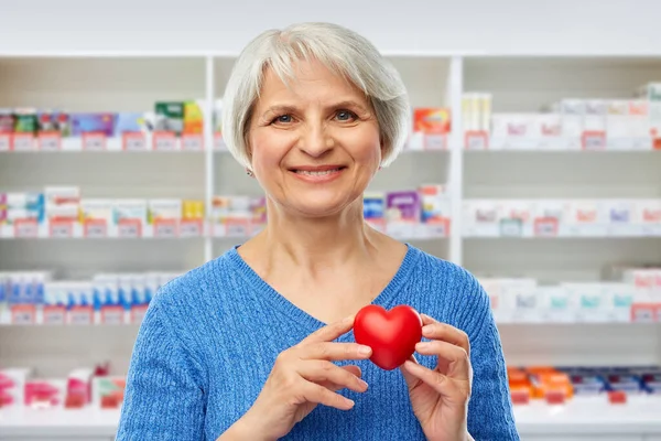 Mujer mayor sonriente con corazón rojo — Foto de Stock