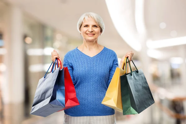 Senior kvinna med shoppingväskor över grå — Stockfoto