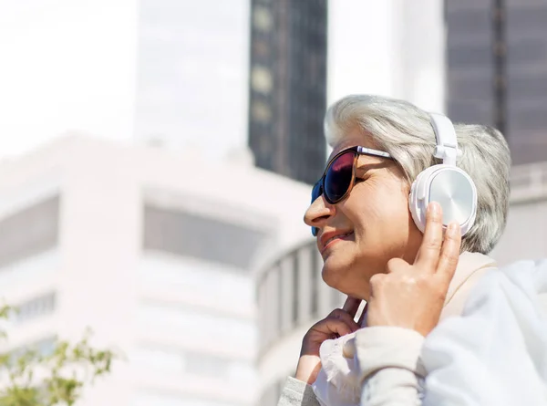 Vieille femme dans casque écoute de la musique dans la ville — Photo