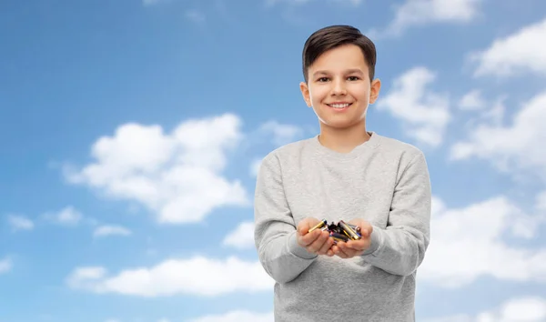 Улыбающийся мальчик держит кучу щелочных батареек — стоковое фото