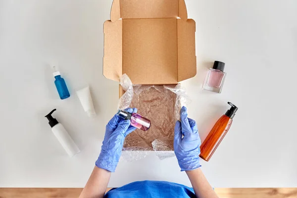 Mains dans des gants emballage boîte de colis avec des cosmétiques — Photo