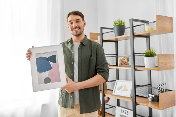 man decorating home with picture in frame
