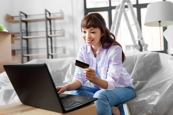 Mulher com laptop e cartão de crédito na nova casa — Fotografia de Stock