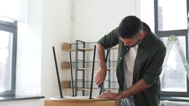Happy man assembling coffee table at new home — Stock Video