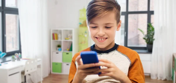 Menino com mensagens de texto smartphone ou jogar em casa — Fotografia de Stock