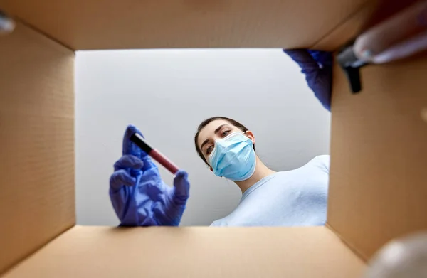 Femme en masque déballage boîte de colis avec des cosmétiques — Photo