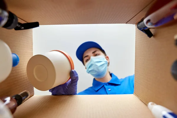 Vrouw in masker verpakking pakket doos met cosmetica — Stockfoto