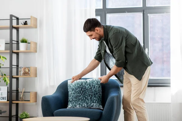 Homme souriant heureux arrangeant coussin de chaise à la maison — Photo