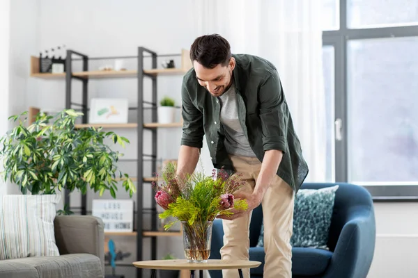 Homme plaçant des fleurs sur la table basse à la maison — Photo