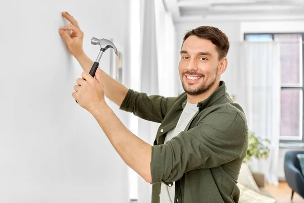 Glimlachende man hameren nagel aan muur thuis — Stockfoto