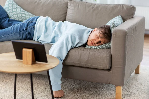 Hombre aburrido con la tableta PC acostado en el sofá en casa — Foto de Stock