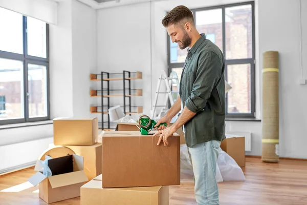 Muž s lepicí páskou balení box v novém domově — Stock fotografie