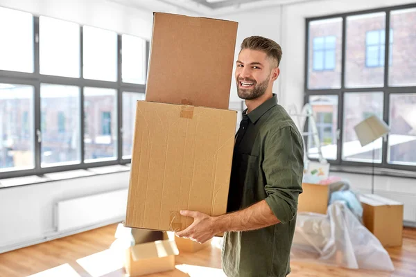 Hombre feliz con cajas mudándose a un nuevo hogar — Foto de Stock