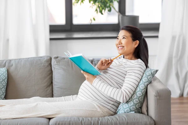 Mujer embarazada feliz escribiendo a diario en casa — Foto de Stock