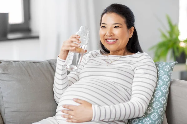Femme enceinte avec de l'eau dans une bouteille en verre à la maison — Photo