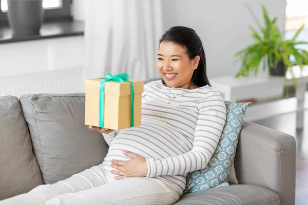 Lykkelig gravid kvinde med gaveæske derhjemme - Stock-foto