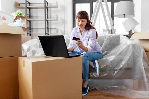 Frau mit Laptop und Kreditkarte im neuen Zuhause — Stockfoto