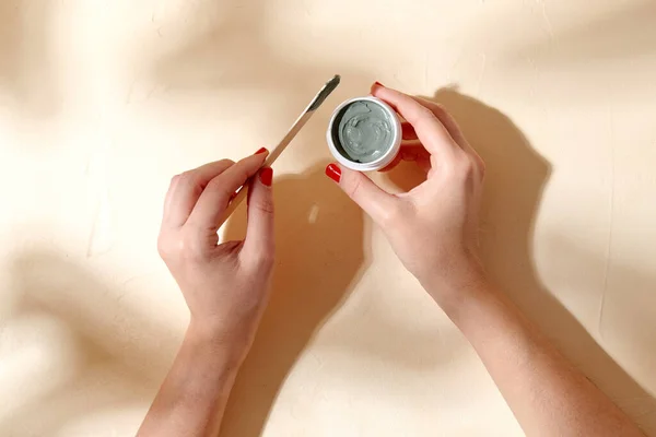 Mãos segurando frasco de máscara de barro cosmético azul — Fotografia de Stock