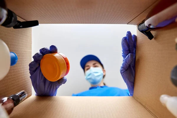 Woman in mask packing parcel box with cosmetics — Stock Photo, Image