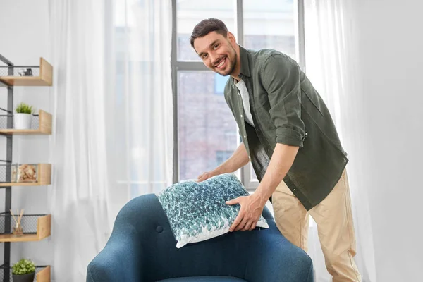 Feliz sorrindo homem arranjando almofada de cadeira em casa — Fotografia de Stock