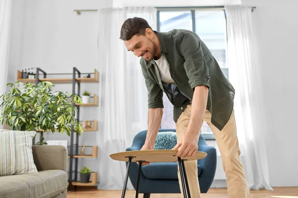 Homme plaçant la table basse à côté du canapé à la maison — Photo