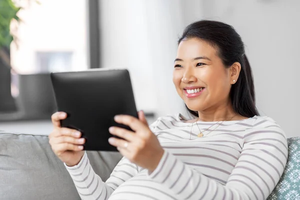 Feliz embarazada mujer asiática con tableta pc en casa — Foto de Stock