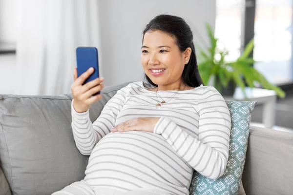 Mulher grávida feliz com smartphone em casa — Fotografia de Stock