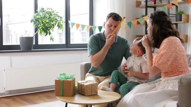 Famille heureuse avec des cadeaux et des ventilateurs de fête à la maison — Video