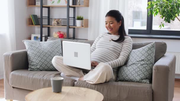 Wanita asia hamil yang bahagia dengan laptop di rumah — Stok Video