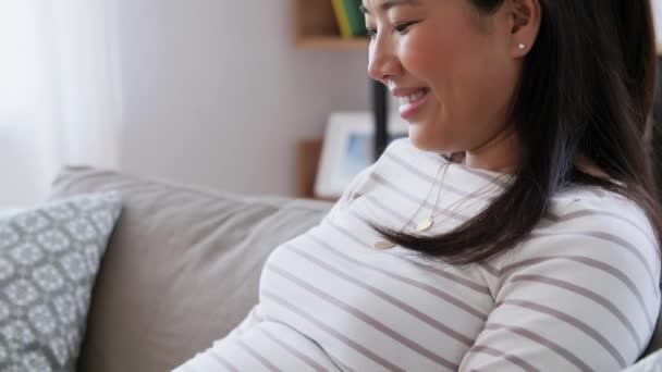 Счастливая беременная азиатка с ноутбуком дома — стоковое видео
