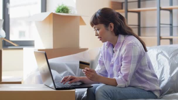 Mujer con portátil y tarjeta de crédito en el nuevo hogar — Vídeos de Stock