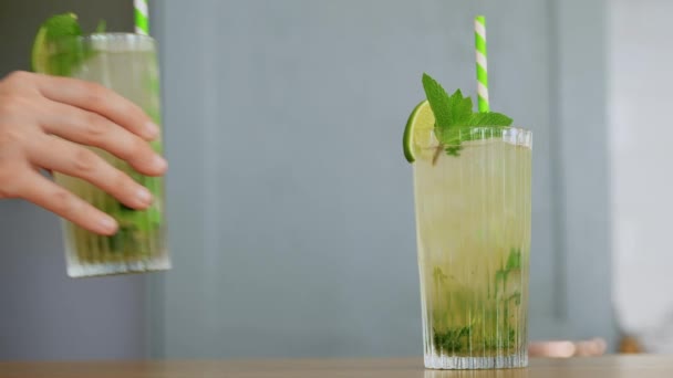 Mano poner vaso de mojito cóctel en la mesa — Vídeos de Stock