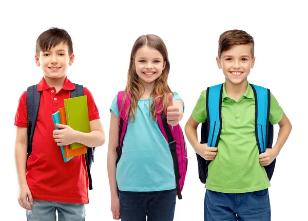 Šťastné děti se školními taškami ukazujícími palce nahoru — Stock fotografie