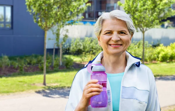 Спортивная старшая женщина с бутылкой воды в городе — стоковое фото