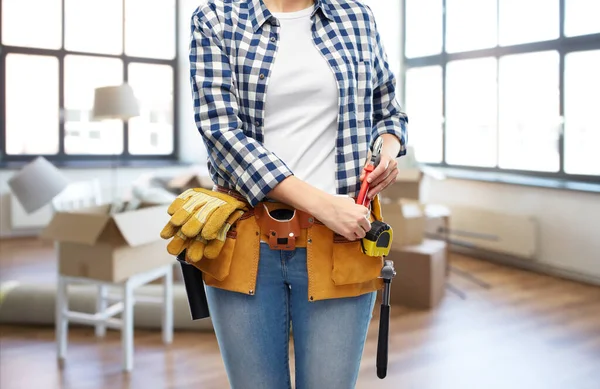 Mujer con herramientas de trabajo en el cinturón en el nuevo hogar —  Fotos de Stock