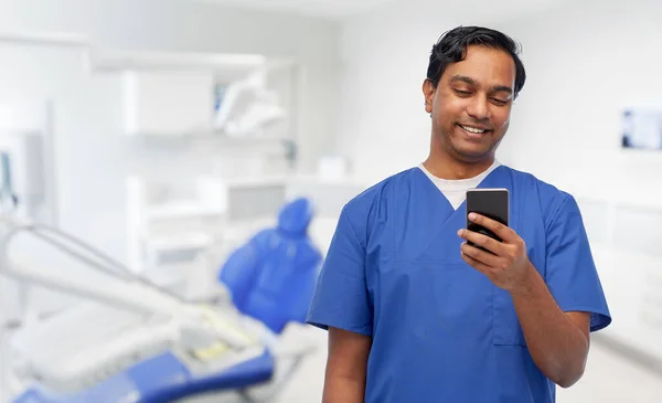 Lächelnder Arzt mit Smartphone in Zahnarztpraxis — Stockfoto