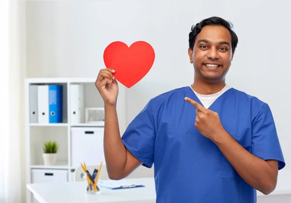 Uśmiechnięty lekarz z czerwonym sercem na schowku — Zdjęcie stockowe