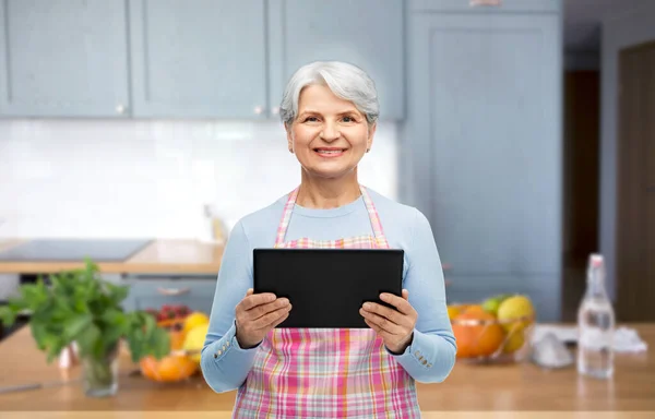 Mulher sênior sorridente com tablet pc na cozinha — Fotografia de Stock