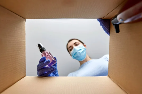 Woman in mask unpacking parcel box with cosmetics — Stock Photo, Image