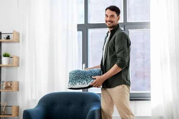 Feliz sorrindo homem arranjando almofada de cadeira em casa — Fotografia de Stock