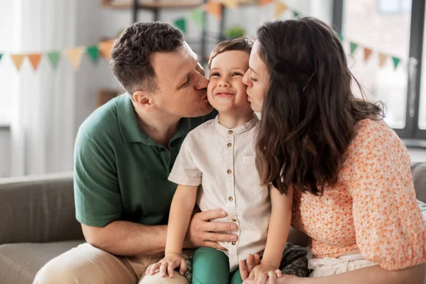 Pais felizes beijando pequeno filho na festa de aniversário — Fotografia de Stock