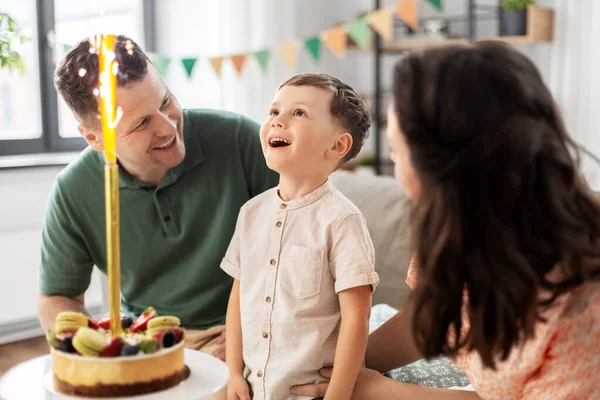 Família feliz com bolo de aniversário em casa — Fotografia de Stock