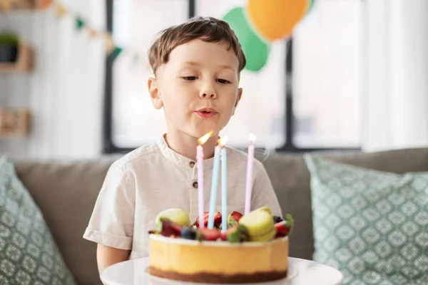 Feliz niño soplando velas en pastel de cumpleaños — Foto de Stock