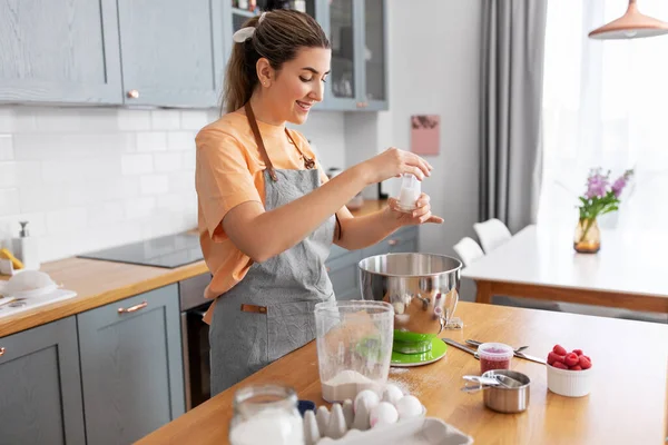 Happy young woman cooking food on kitchen at home — Stock Photo, Image