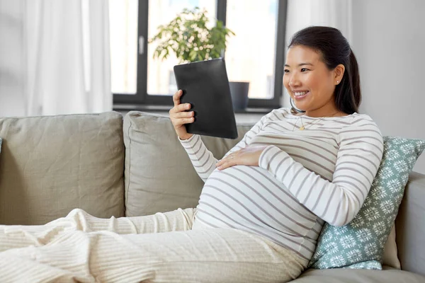 Felice donna asiatica incinta con tablet pc a casa — Foto Stock