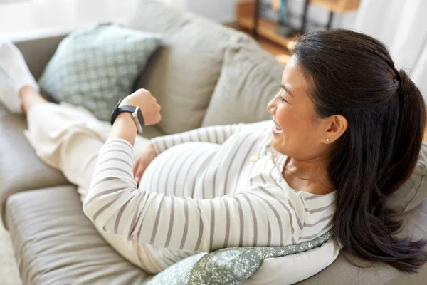 Mujer embarazada feliz con reloj inteligente en casa — Foto de Stock