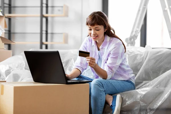 Mulher com laptop e cartão de crédito na nova casa — Fotografia de Stock