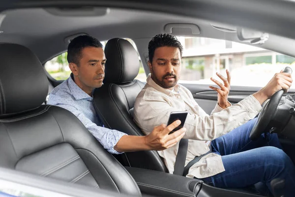 Αρσενικό επιβάτη δείχνει smartphone στον οδηγό του αυτοκινήτου — Φωτογραφία Αρχείου